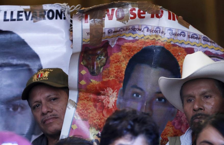 Parents and relatives of the 43 missing teachers college students hold banners depicting their loved ones as they give a press conference at the national palace in Mexico City, Thusday, Jan. 9, 2020. Family members met with Mexico's President Andres Manuel Lopez Obrador for to call for justice more than five years after the Ayotzinapa students were allegedly taken from buses by local police and turned over to a drug gang. (AP Photo/Marco Ugarte)