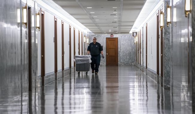 A workman walks through the empty corridors of the Dirksen Senate Office Building on Capitol Hill as lawmakers negotiate on the emergency coronavirus response legislation, in Washington, Wednesday, March 18, 2020. (AP Photo/J. Scott Applewhite) **FILE**