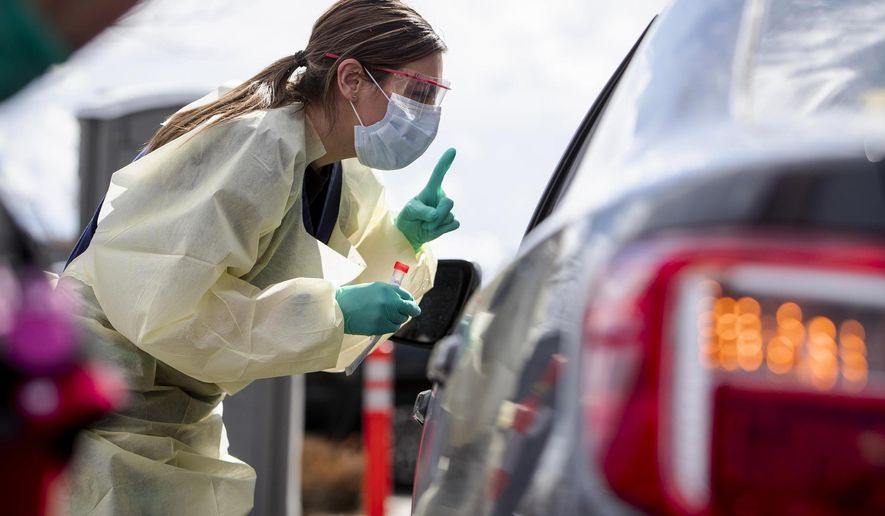 In this file photo, Ashley Layton, an LPN at St. Luke's Meridian Medical Center, communicates with a person before taking swab sample at a special outdoor drive-thru screening station for COVID-19 coronavirus Tuesday, March 17, 2020. (Darin Oswald/Idaho Statesman via AP) **FILE**