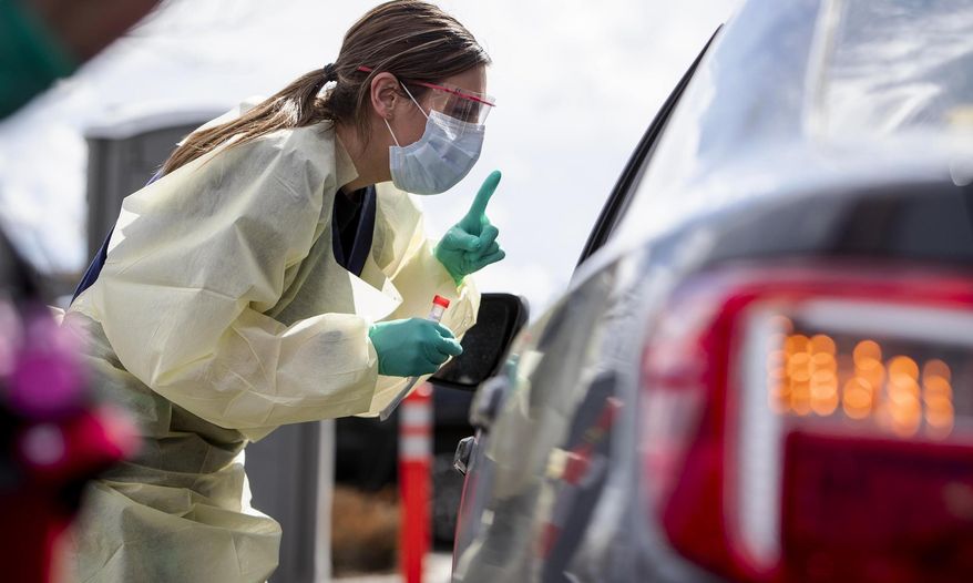 In this file photo, Ashley Layton, an LPN at St. Luke's Meridian Medical Center, communicates with a person before taking swab sample at a special outdoor drive-thru screening station for COVID-19 coronavirus Tuesday, March 17, 2020. (Darin Oswald/Idaho Statesman via AP) **FILE**