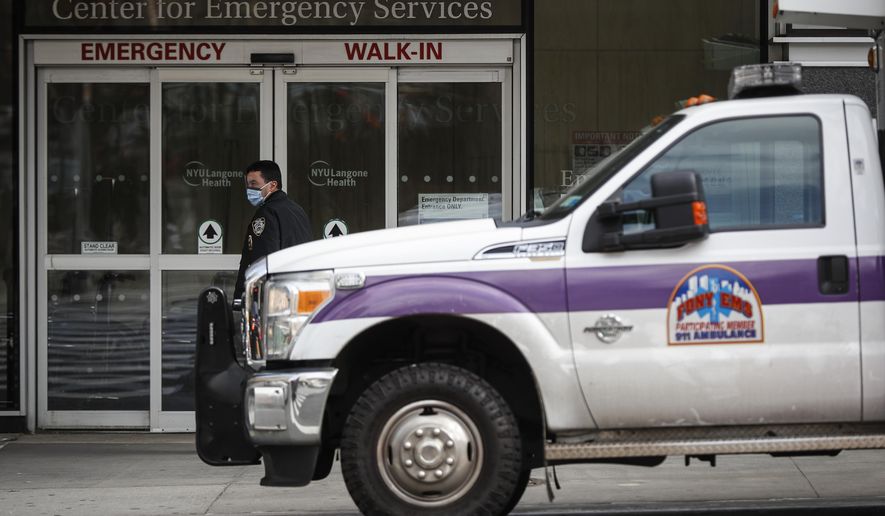 In this March 16, 2020, photo an NYPD officer wearing a protective face mask monitors the outside of the NYU Langone Hospital Emergency room entrance in New York. Brooklyn’s district attorney announced Tuesday, March 17, that because of the crisis his office is declining to prosecute low-level offenses that don’t jeopardize public safety. (AP Photo/John Minchillo, File)