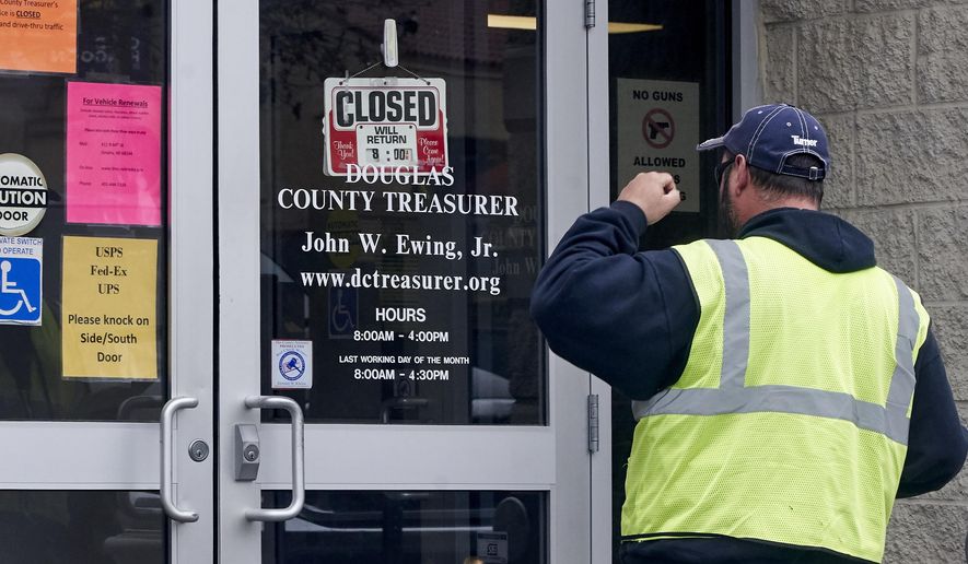 A man is confronted with a closed sign at the Douglas County Treasurer's office in Omaha, Neb., Wednesday, March 18, 2020. In-person services were suspended due to the coronavirus outbreak. (AP Photo/Nati Harnik)