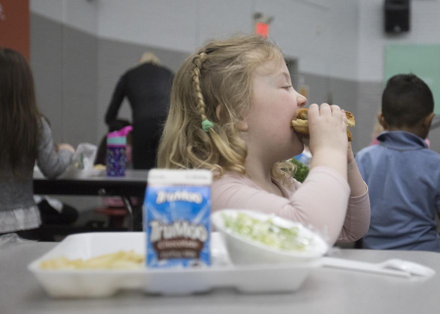 In this Friday, March 13, 2020 photo, Amy Thompson, 5, eats a chicken sandwich during lunch at Rivermont elementary school in Chattanooga, Tenn. Hamilton County School District announced yesterday that they would be closing school from March 16-30, which will leave many children who depend on the federal free lunch program for meals without food. (Troy Stolt/Chattanooga Times Free Press via AP)