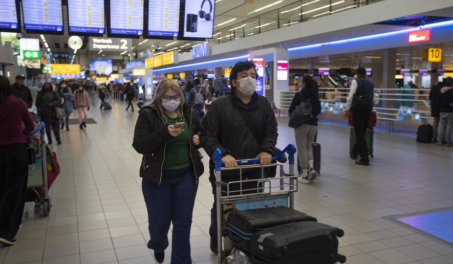 Two travelers wearing face masks walk to the check-in counter at Schiphol Airport which closed five out of its seven piers and canceled a vast number of flights, near Amsterdam, Netherlands, Thursday, March 19, 2020. The country has come to a near standstill as the government sought to prevent the further spread of coronavirus in the Netherlands. For most people, the new coronavirus causes only mild or moderate symptoms, such as fever and cough. For some, especially older adults and people with existing health problems, it can cause more severe illness, including pneumonia. (AP Photo/Peter Dejong)