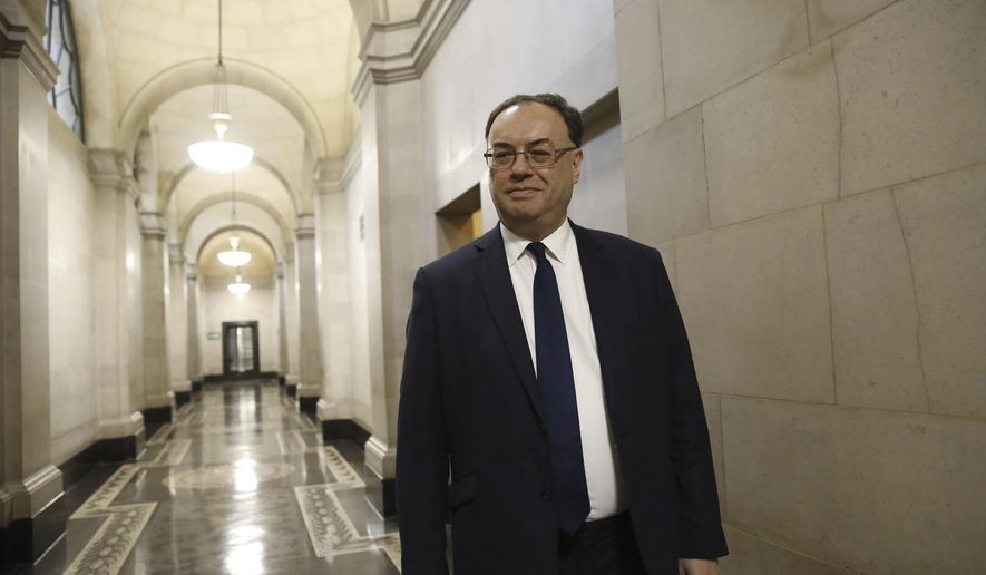 FILE - In this file photo dated Monday March 16, 2020, The Bank of England Governor Andrew Bailey poses for a photograph at the central bank in London. The Bank of England slashed its key interest rate to 0.1%, on Thursday March 19, 2020, its lowest-ever level, amid global economic turmoil sparked by the coronavirus pandemic. For some people the COVID-19 coronavirus causes mild or moderate symptoms, but for some it causes severe illness.(Tolga Akmen/AP, FILE)