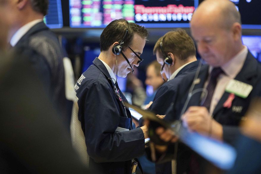 This photo provided by the New York Stock Exchange, Thursday, March 19, 2020, shows trader Gregory Rowe, center, as he works on the trading floor. Stocks are see-sawing between gains and losses in midday trading on Wall Street Thursday, but the moves are more subdued than the wild jabs that have dominated recent weeks. (NYSE Photo by Alyssa Ringler via AP)