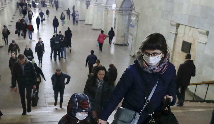 A woman with her child wear medical masks walk inside the Komsomolskaya Metro (subway) station in Moscow, Russia, Wednesday, March 18, 2020. Authorities in Russia are taking vast measures to prevent the spread of the disease in the country. The measures include closing the border for all foreigners, shutting down schools for three weeks, sweeping testing and urging people to stay home. For most people, the new coronavirus causes only mild or moderate symptoms. For some it can cause more severe illness. (AP Photo/Pavel Golovkin)