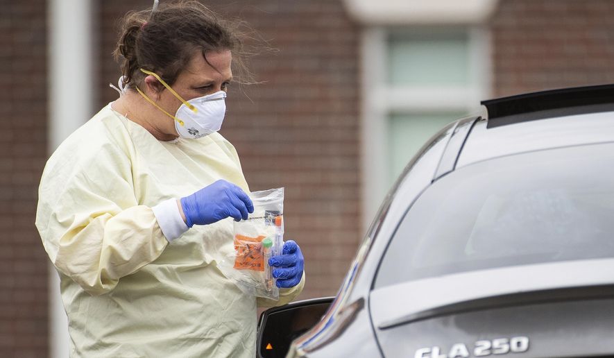 A staff member collects a sample from a patient at Waddell Family Medicine as Athens-Limestone Hospital opens a flu and fever clinic on Thursday, March 19, 2020, in Athens, Ala. Patients will only be tested for COVID-19 if indicated by their exam or ordered by the physician or provider. . (Dan Busey/The Decatur Daily via AP)