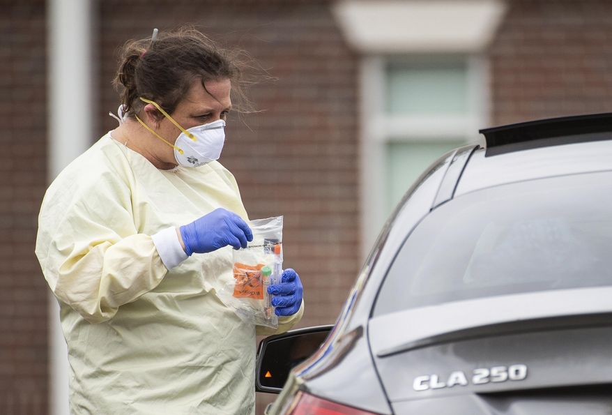 A staff member collects a sample from a patient at Waddell Family Medicine as Athens-Limestone Hospital opens a flu and fever clinic on Thursday, March 19, 2020, in Athens, Ala. Patients will only be tested for COVID-19 if indicated by their exam or ordered by the physician or provider. . (Dan Busey/The Decatur Daily via AP)