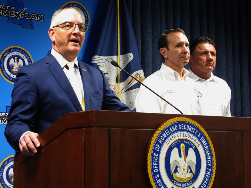 Louisiana Gov. John Bel Edwards speaks about the coronavirus, while Attorney General Jeff Landry, center, and LSU football coach Ed Orgeron listen, on Wednesday, March 18, 2020, in Baton Rouge, La. (AP Photo/Melinda Deslatte)