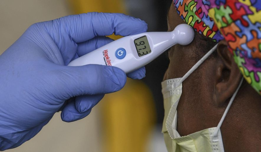 A woman gets her temperature read as normal before going to work at AnMed Health Campus Emergency Department entrance in Anderson, S.C. in Anderson Thursday, March 19, 2020. (Ken Ruinard /The Independent-Mail via AP)
