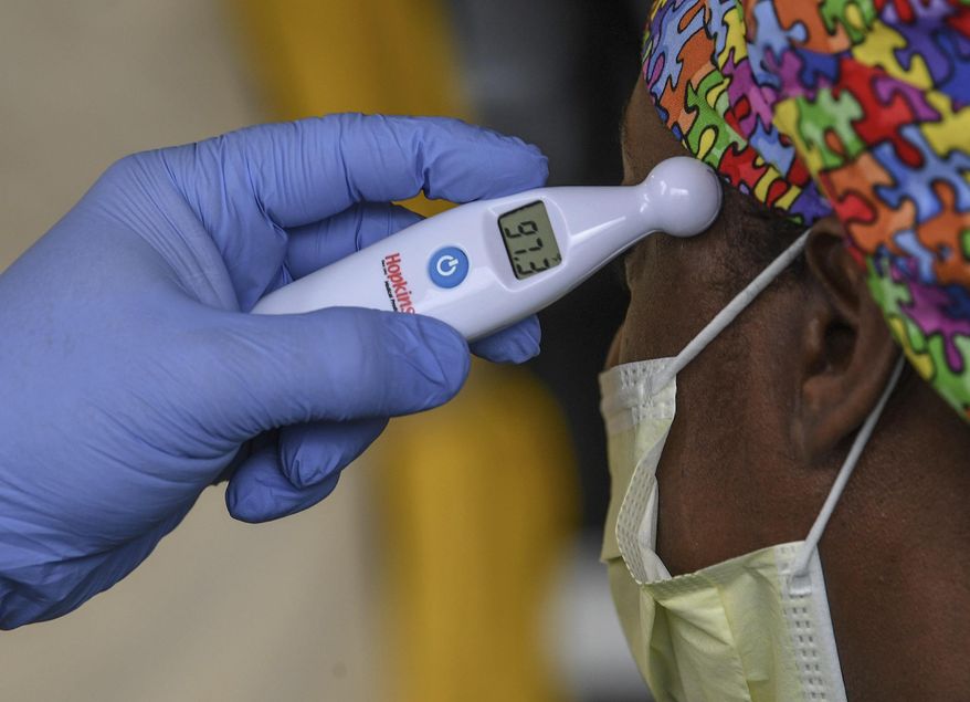 A woman gets her temperature read as normal before going to work at AnMed Health Campus Emergency Department entrance in Anderson, S.C. in Anderson Thursday, March 19, 2020. (Ken Ruinard /The Independent-Mail via AP)