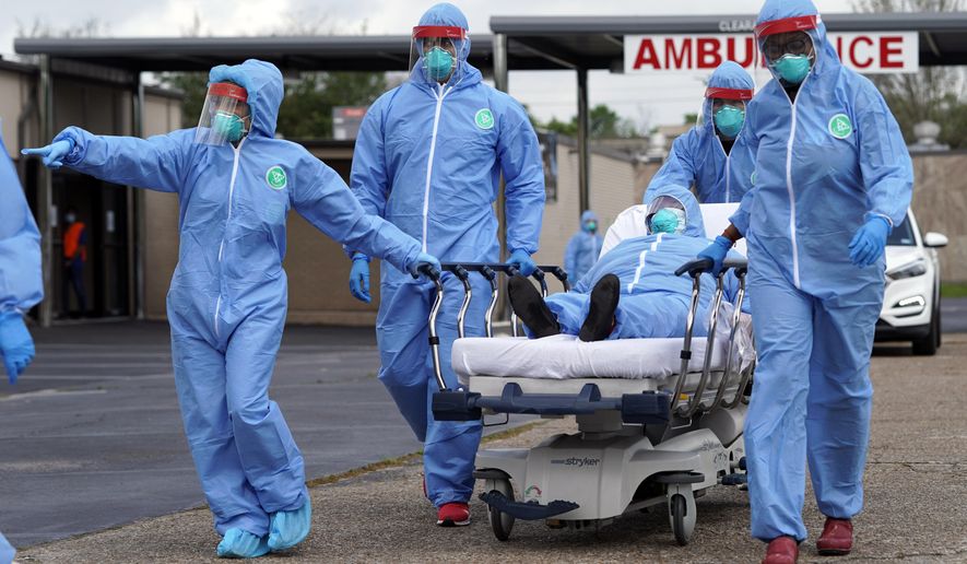 A woman is taken on a stretcher by healthcare professionals into the United Memorial Medical Center after going through testing for COVID-19 Thursday, March 19, 2020, in Houston. People were lined up in their cars in a line that stretched over two miles to be tested in the drive-thru testing for coronavirus. (AP Photo/David J. Phillip)