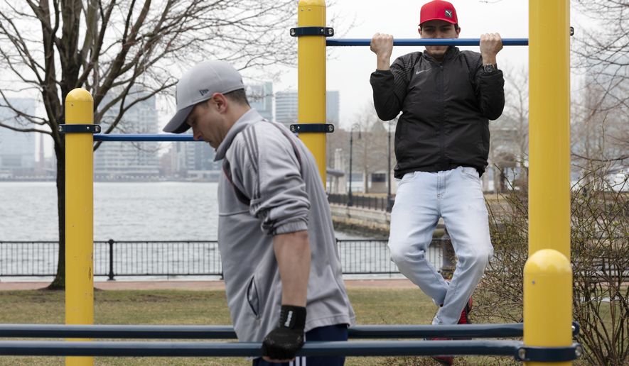 In this file photo, two men exercise in Piers Park in Boston, Friday, March, 20, 2020. The gym they usually use is closed due to the coronavirus. (AP Photo/Michael Dwyer) **FILE**