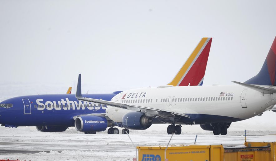 A Delta Airlines jetliner waits for a Southwest jetliner to taxi pst on the way to a runway for take off from Denver International Airport as travelers deal with the spread of coronavirus Friday, March 20, 2020, in Denver. According to the World Health Organization, most people recover in about two to six weeks depending on the severity of the COVID-19 illness. (AP Photo/David Zalubowski)