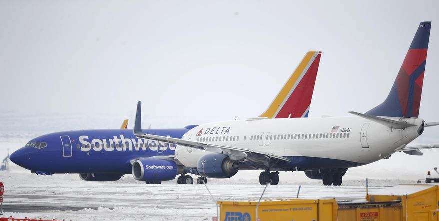 A Delta Airlines jetliner waits for a Southwest jetliner to taxi pst on the way to a runway for take off from Denver International Airport as travelers deal with the spread of coronavirus Friday, March 20, 2020, in Denver. According to the World Health Organization, most people recover in about two to six weeks depending on the severity of the COVID-19 illness. (AP Photo/David Zalubowski)