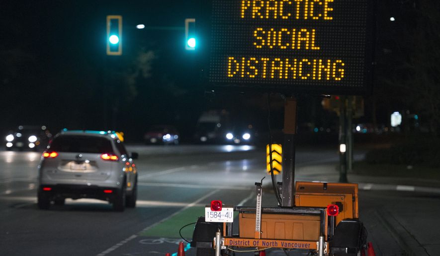 FILE - In this Wednesday, March 18, 2020 file photo, a sign reminding people about "social distancing" in the midst of the COVID-19 coronavirus outbreak stands next to a roadway in North Vancouver, British Columbia, Canada. Many see “social distancing” to be the greatest pandemic-era addition the vernacular yet — easily understood phrasing that’s helped communicate to millions that they need to keep a safe berth to avoid spreading the virus. (Jonathan Hayward/The Canadian Press via AP)