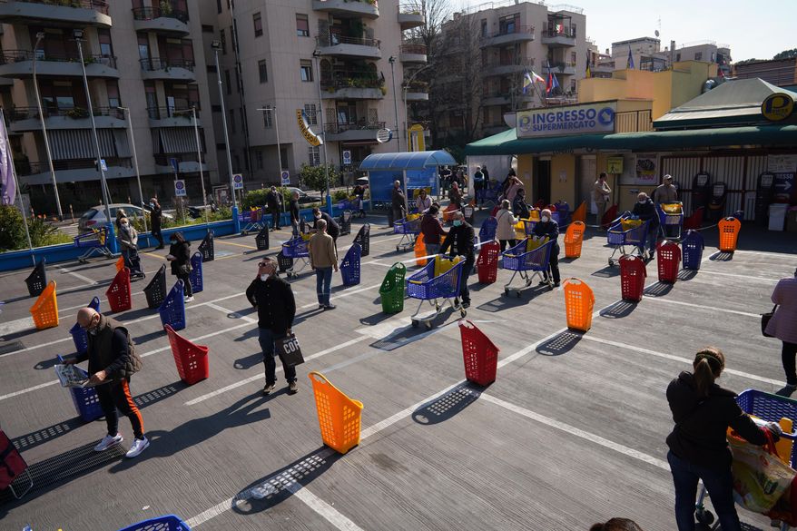 People stand apart as they line up to enter a supermarket in Rome, Friday, March 20, 2020. For most people, the new coronavirus causes only mild or moderate symptoms. For some it can cause more severe illness. (AP Photo/Andrew Medichini)
