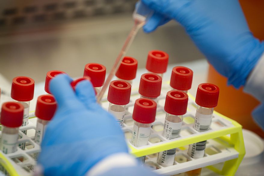 In this Wednesday, March 11, 2020, file photo, a technician prepares COVID-19 patient samples for testing at a laboratory in New York's Long Island. (AP Photo/John Minchillo) ** FILE **