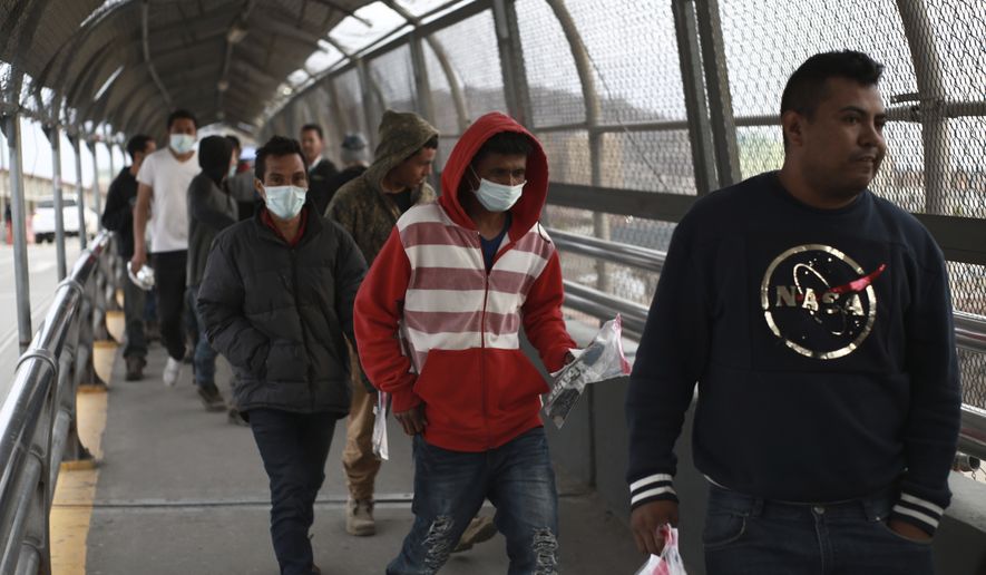 Central American migrants seeking asylum, some wearing protective face masks, return to Mexico via the international bridge at the U.S-Mexico border that joins Ciudad Juarez and El Paso, Saturday, March 21, 2020. Mexico and the U.S. are restricting travel over their busy shared border as they try to control the spread of the coronavirus pandemic. (AP Photo/Christian Chavez)