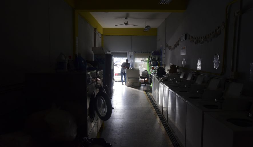 Laundromat owner Jesus Vazquez pauses before closing his shop to comply with the government&#39;s curfew aimed at curbing the spread of the new coronavirus, which is shuttering all non-essential businesses for two weeks in San Juan, Puerto Rico, Friday, March 20, 2020. (AP Photo/Carlos Giusti)