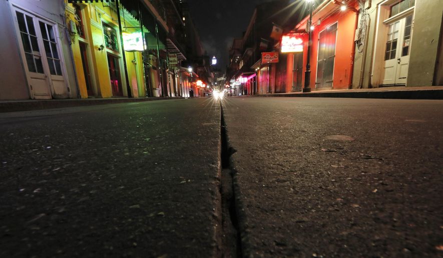 FILE - In this Thursday, March 19, 2020, file photo, a view of the nearly deserted scene on Bourbon Street, which is normally bustling with tourists and revelers, in the French Quarter of New Orleans. In the city here, the old saying “Let the good times roll” has given way to a new municipal maxim: “Wash your hands.” Due to the coronavirus outbreak, New Orleans has joined those places shutting down bars, eliminating restaurant dining and banning crowds. (AP Photo/Gerald Herbert, File)