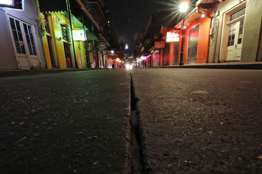 FILE - In this Thursday, March 19, 2020, file photo, a view of the nearly deserted scene on Bourbon Street, which is normally bustling with tourists and revelers, in the French Quarter of New Orleans. In the city here, the old saying “Let the good times roll” has given way to a new municipal maxim: “Wash your hands.” Due to the coronavirus outbreak, New Orleans has joined those places shutting down bars, eliminating restaurant dining and banning crowds. (AP Photo/Gerald Herbert, File)