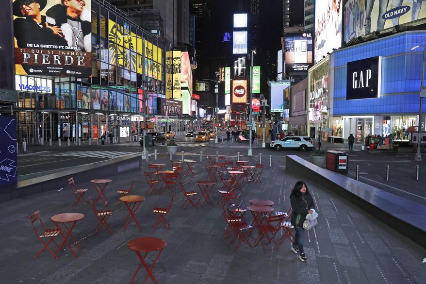 A woman walks through a lightly trafficked Times Square in New York, March 16, 2020. (AP Photo/Seth Wenig)
