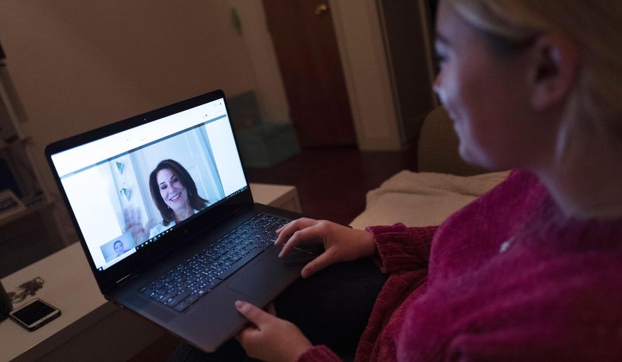 FILE - In this Jan. 14, 2019 photo, a patient sits in the living room of her apartment in the Brooklyn borough of New York during a telemedicine video conference with Dr. Deborah Mulligan. Telemedicine often involves diagnosing and treating a new health problem but is also used to keep tabs on an existing, long-term condition. (AP Photo/Mark Lennihan)