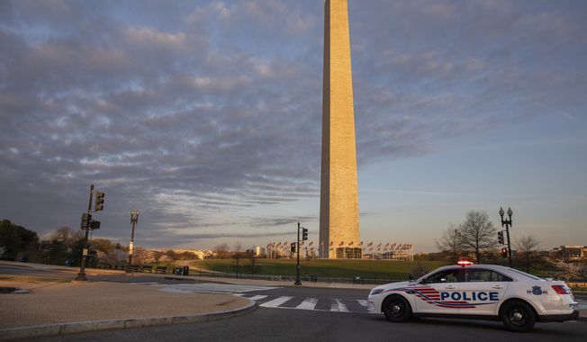 A Metropolitan Police Department car blocks the road near the Washington Monument in an effort to discourage crowds from visiting the cherry blossom trees in full bloom, Sunday, March 22, 2020, in Washington, D.C. (AP Photo/Jacquelyn Martin) ** FILE **