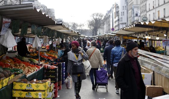 People walk in the open air market of Belleville, in Paris, Friday, March 20, 2020. French President Emmanuel Macron said that for 15 days starting at noon on Tuesday, people will be allowed to leave the place they live only for necessary activities such as shopping for food, going to work or taking a walk. For most people, the new coronavirus causes only mild or moderate symptoms. For some it can cause more severe illness, especially in older adults and people with existing health problems. (AP Photo/Thibault Camus)