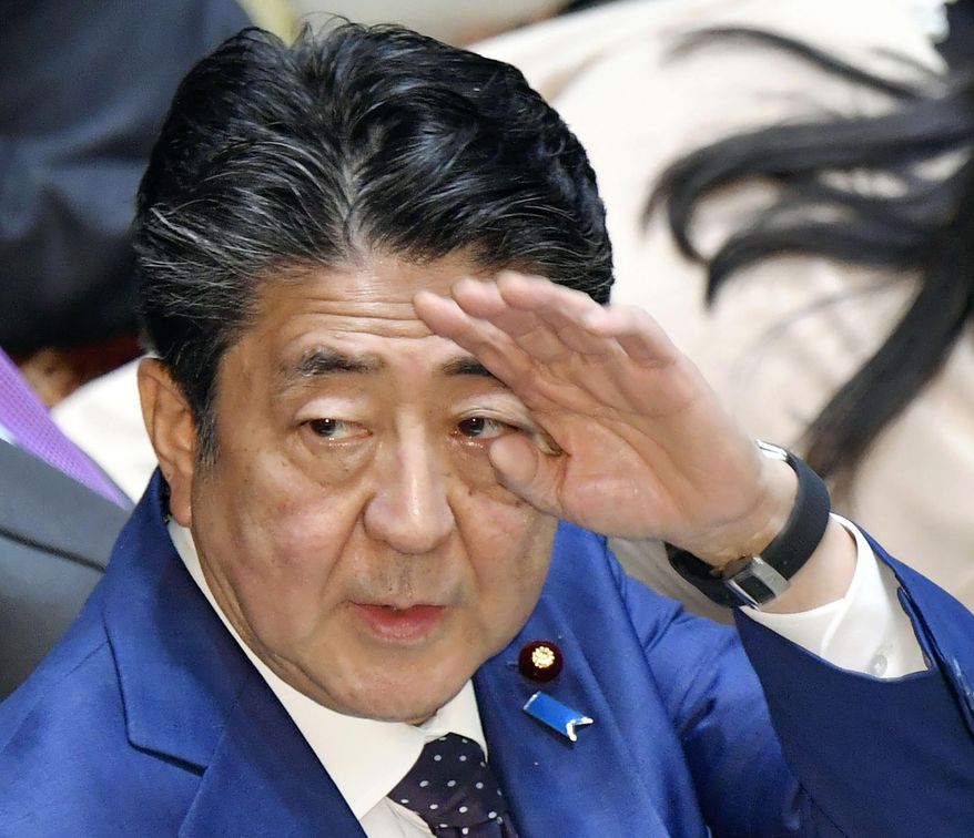 Japan’s Prime Minister Shinzo Abe raises his hand during a parliamentary session in Tokyo Monday, March 23, 2020. Abe said a postponement of Tokyo Olympics would be unavoidable if the games cannot be held in a complete way because of the coronavirus pandemic. (Yoshitaka Sugawara/Kyodo News via AP)