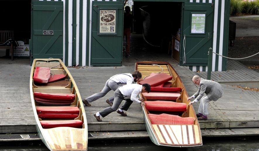 Staff put their boats away on the banks of the Avon River in central Christchurch, New Zealand, Monday, March 23, 2020. New Zealand Prime Minister Jacinda Ardern announced Monday that schools and non-essential services across New Zealand will be closed as part of the measures as the government put the country in lockdown to try to stop the spread of coronavirus pandemic. (AP Photo/Mark Baker)