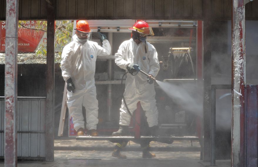 Sri Lankan fire brigade personnel spray disinfectants at a bus terminal in Colombo, Sri Lanka, Sunday, March 22, 2020. For most people, the new coronavirus causes only mild or moderate symptoms. For some it can cause more severe illness. (AP Photo/Eranga Jayawardena)