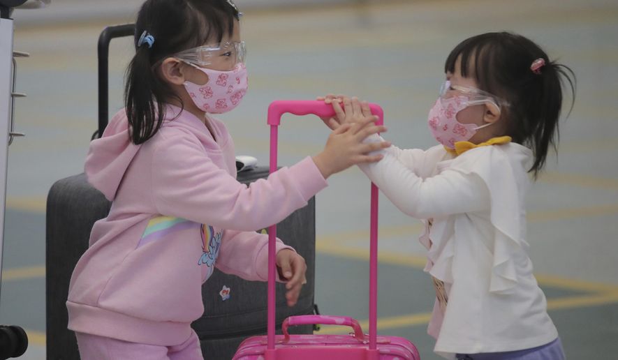 Young passengers wear face masks to protect against the coronavirus as they arrive at the Hong Kong airport, Monday, March 23, 2020. For most, the coronavirus causes only mild or moderate symptoms, such as fever and cough. But for a few, especially older adults and people with existing health problems, it can cause more severe illnesses, including pneumonia. (AP Photo/Kin Cheung)