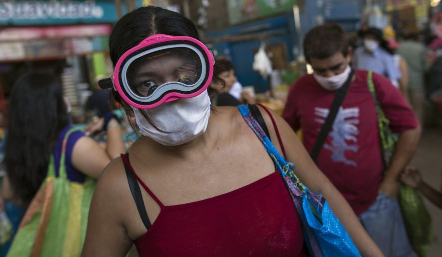 A woman wears a scuba mask and a surgical mask as a precaution against the spread of the new coronavirus, while buying food in a popular market in Lima, Peru, Monday, March 23, 2020. The vast majority of people recover from the COVID-19 disease. (AP Photo/Rodrigo Abd) **FILE**