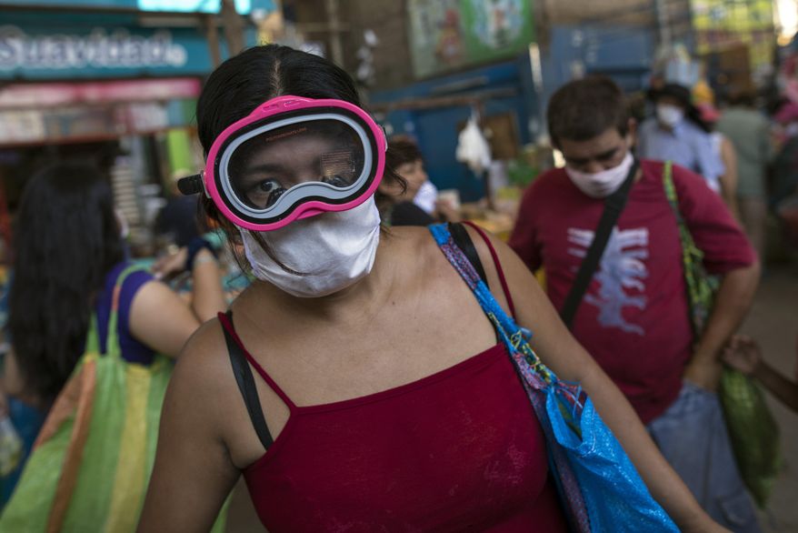 A woman wears a scuba mask and a surgical mask as a precaution against the spread of the new coronavirus, while buying food in a popular market in Lima, Peru, Monday, March 23, 2020. The vast majority of people recover from the COVID-19 disease. (AP Photo/Rodrigo Abd) **FILE**