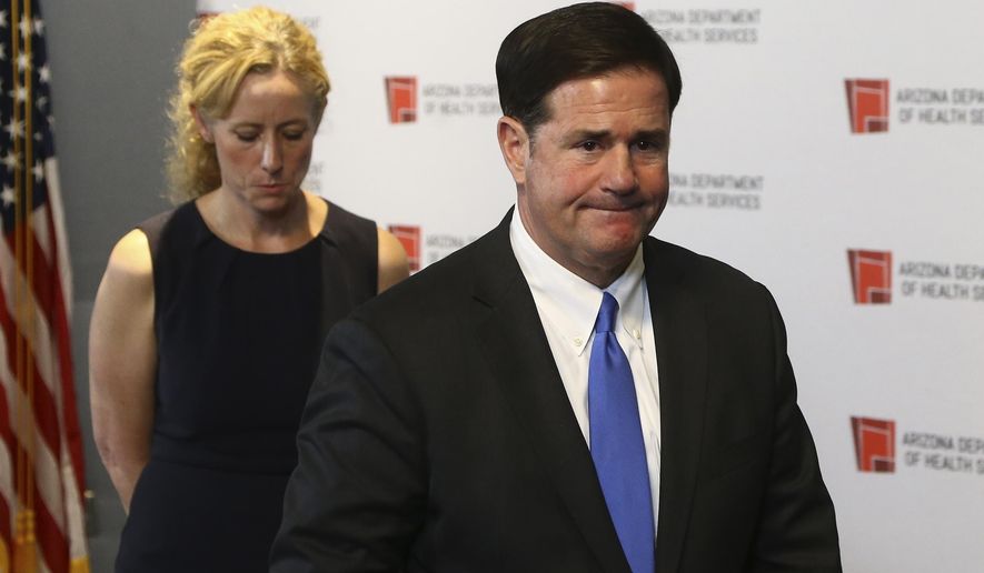 Arizona Gov. Doug Ducey, right, and Arizona Department of Health Services Director Dr. Cara Christ, left, exit a news conference after providing an update on the coronavirus at the Arizona State Public Health Laboratory Monday, March 23, 2020, in Phoenix. (AP Photo/Ross D. Franklin)
