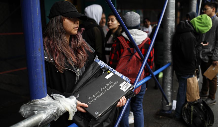 Anna Louisa, 18, receives her school laptop for home study at the Lower East Side Preparatory School, Thursday, March 19, 2020, in New York, as coronavirus restrictions shuttered classrooms throughout the city. New York Gov. Andrew Cuomo tightened work-from-home rules as confirmed cases continued to climb in New York, an expected jump as testing becomes more widespread. (AP Photo/John Minchillo)