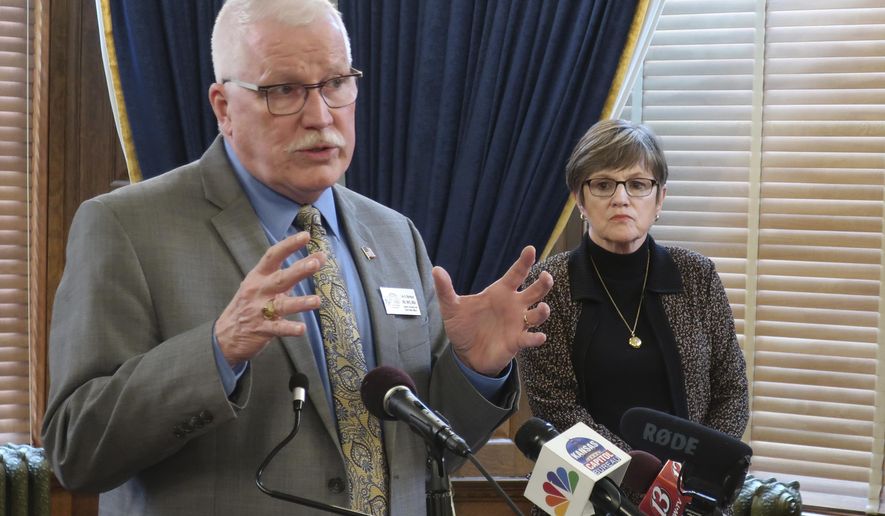 Dr. Lee Norman, Kansas secretary of health and environment, answers questions about the coronavirus pandemic as Gov. Laura Kelly watches during a news conference, Monday, March 23, 2020, at the Statehouse in Topeka, Kan. Six counties with about 1 million of the state's 2.9 million residents have issued shelter-in-place orders and Kelly says she's going to impose stricter rules for public gatherings. (AP Photo/John Hanna)