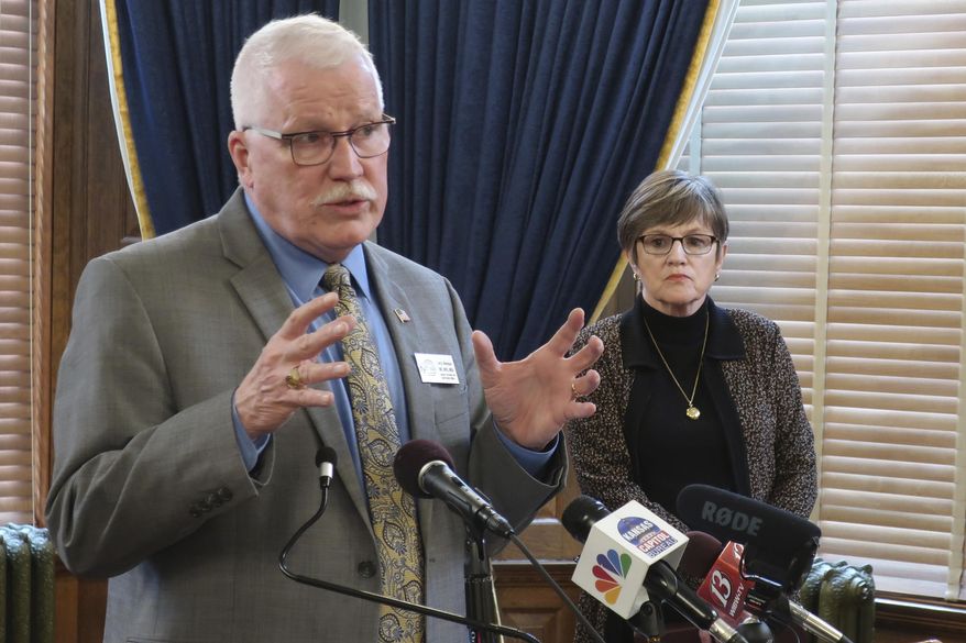 Dr. Lee Norman, Kansas secretary of health and environment, answers questions about the coronavirus pandemic as Gov. Laura Kelly watches during a news conference, Monday, March 23, 2020, at the Statehouse in Topeka, Kan. Six counties with about 1 million of the state's 2.9 million residents have issued shelter-in-place orders and Kelly says she's going to impose stricter rules for public gatherings. (AP Photo/John Hanna)
