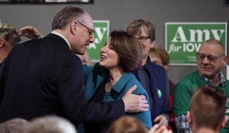 In this Feb. 1, 2020, file photo, Democratic presidential candidate Sen. Amy Klobuchar, D-Minn., center, gets a kiss from husband John Bessler, upon arriving at a rally in Sioux City, Iowa. Sen. Klobuchar announced Monday, March 23, that her husband has tested positive for the coronavirus. (AP Photo/Gene J. Puskar File)