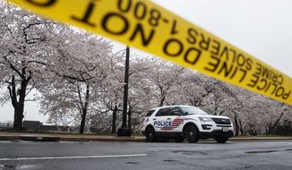 A Washington, D.C., Metropolitan Police vehicle is parked on the other side of a tape police line along the Tidal Basin as cherry blossoms cover the trees, in Washington, Monday, March 23, 2020. (AP Photo/Carolyn Kaster) **FILE**