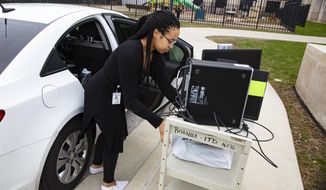 An employee at the Indiana Department of Revenue moves her computer equipment from her office at the State office complex in Indianapolis, Tuesday, March 24, 2020, to allow her to work from home. Indiana Gov. Eric Holcomb ordered state residents to remain in their homes except when they are at work or for permitted activities, such as taking care of others, obtaining necessary supplies, and for health and safety. The order is in effect from March 25 to April 7. (AP Photo/Michael Conroy)