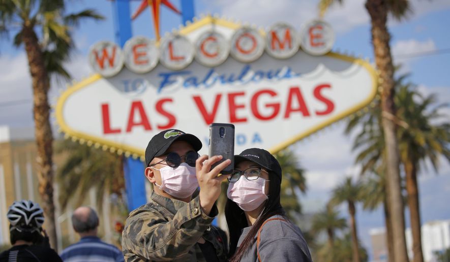 In this March 21, 2020, photo, a couple wearing face masks take a selfie at the &amp;quot;Welcome to Fabulous Las Vegas Nevada&amp;quot; sign amid a shutdown of casinos along the Las Vegas Strip due to coronavirus in Las Vegas. The emerging coronavirus pandemic has spurred a lawsuit by a Las Vegas attorney with a background in big cases, who is seeking compensation from the Chinese government for more than 32 million small U.S. businesses that have lost income and profits as a result of the outbreak. Eglet seeks class-action status and said Tuesday, March 24, 2020 he believes damages for Chinese &amp;quot;reckless&amp;quot; and &amp;quot;negligent&amp;quot; conduct could be in the trillions of dollars. They seek compensation from the government of China. (AP Photo/John Locher) **FILE**