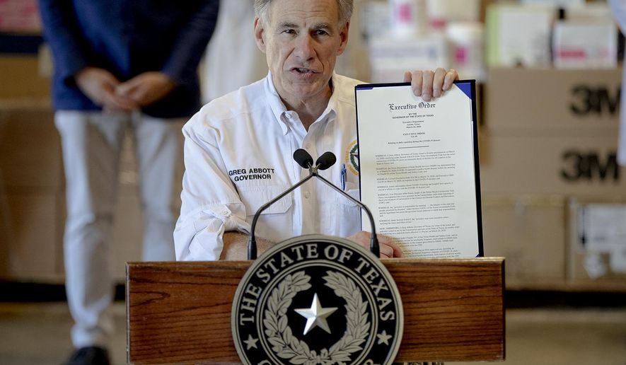 Texas Gov. Greg Abbott shows a new executive order regarding reporting data about the coronavirus during a news conference on Tuesday, March 24, 2020, in Austin, Texas. (Nick Wagner/Austin American-Statesman via AP)