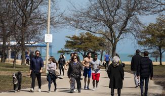 People enjoying warm weather with a stroll along the Lakefront Trail Trail near North Avenue Beach, Wednesday afternoon, March 25, 2020, in Chicago, despite a stay-at-home order from Illinois Gov. J.B. Pritzker during the coronavirus pandemic. The new coronavirus causes mild or moderate symptoms for most people, but for some, especially older adults and people with existing health problems, it can cause more severe illness or death. (Ashlee Rezin Garcia/Chicago Sun-Times via AP)