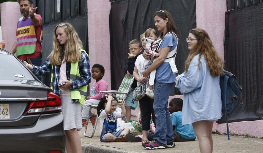 A family of anti-abortion activists stand outside the "Pink House" as the Women's Health Organization clinic, is sometimes called, as they call on patients being dropped off at the facility, to hold off having an abortion, while a clinic escort, signals the driver into their parking lot, Wednesday, March 25, 2020, in Jackson, Miss. The clinic is Mississippi's only state licensed abortion facility. Gov. Tate Reeves told reporters at a press conference on the coronavirus Tuesday that he considers abortion an elective and unnecessary procedure. (AP Photo/Rogelio V. Solis)