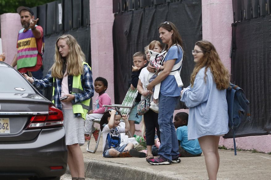 A family of anti-abortion activists stand outside the "Pink House" as the Women's Health Organization clinic, is sometimes called, as they call on patients being dropped off at the facility, to hold off having an abortion, while a clinic escort, signals the driver into their parking lot, Wednesday, March 25, 2020, in Jackson, Miss. The clinic is Mississippi's only state licensed abortion facility. Gov. Tate Reeves told reporters at a press conference on the coronavirus Tuesday that he considers abortion an elective and unnecessary procedure. (AP Photo/Rogelio V. Solis)