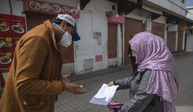 A member of security forces inspects a permit allowing a woman to leave her home, after a health state of emergency was declared and members of the public ordered to a home confinement, in Rabat, Morocco, Sunday, March 22, 2020. For some people the COVID-19 coronavirus causes mild or moderate symptoms, but for some it can cause severe illness including pneumonia.(AP Photo/Mosa&#x27;ab Elshamy)
